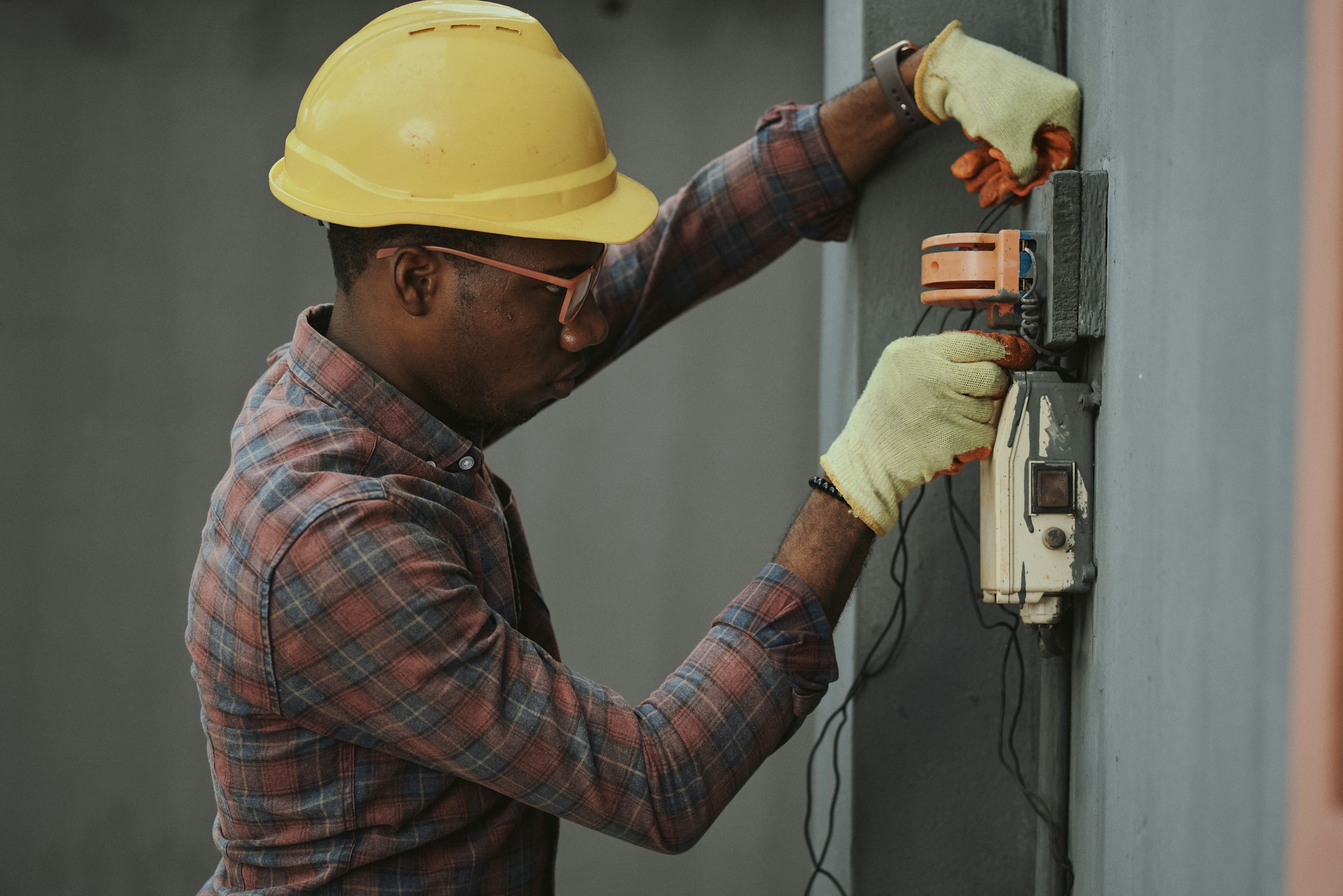 Technician in a hard hat servicing an electrical control panel