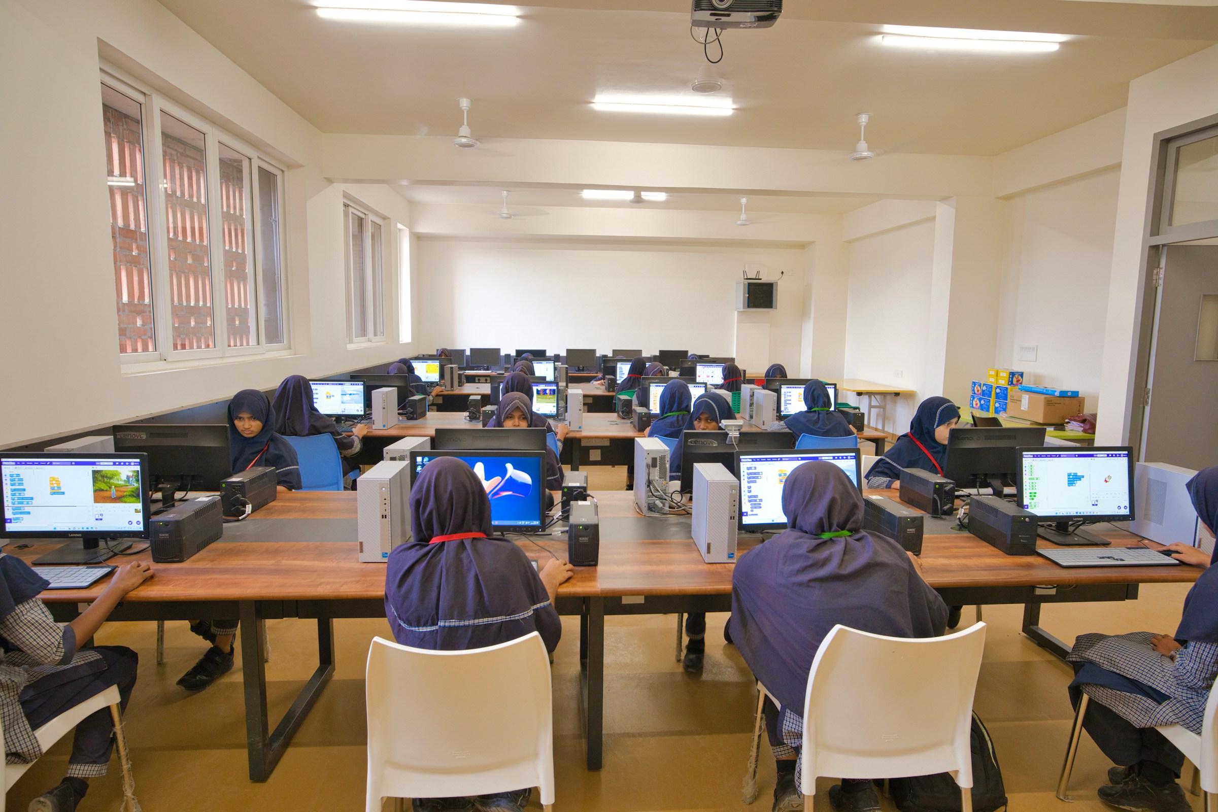 School students in uniform working at desktop computers in a school computer laboratory
