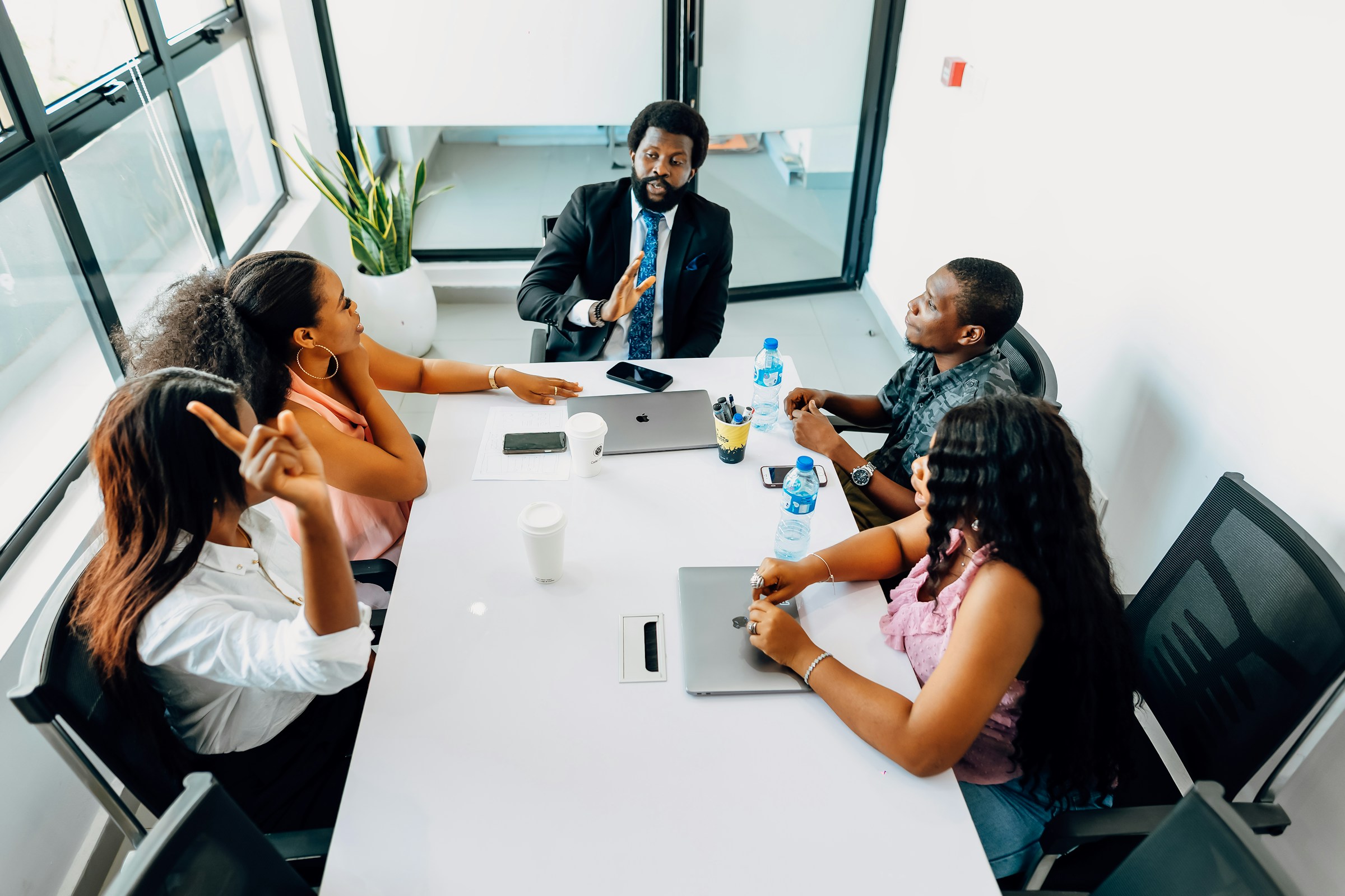 Management team in discussion around a table in a daylit meeting room