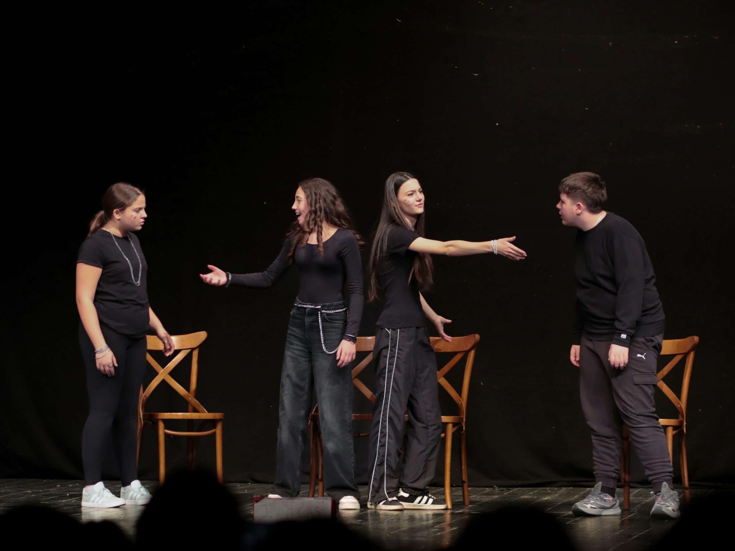Students performing on a darkened stage in front of an audience