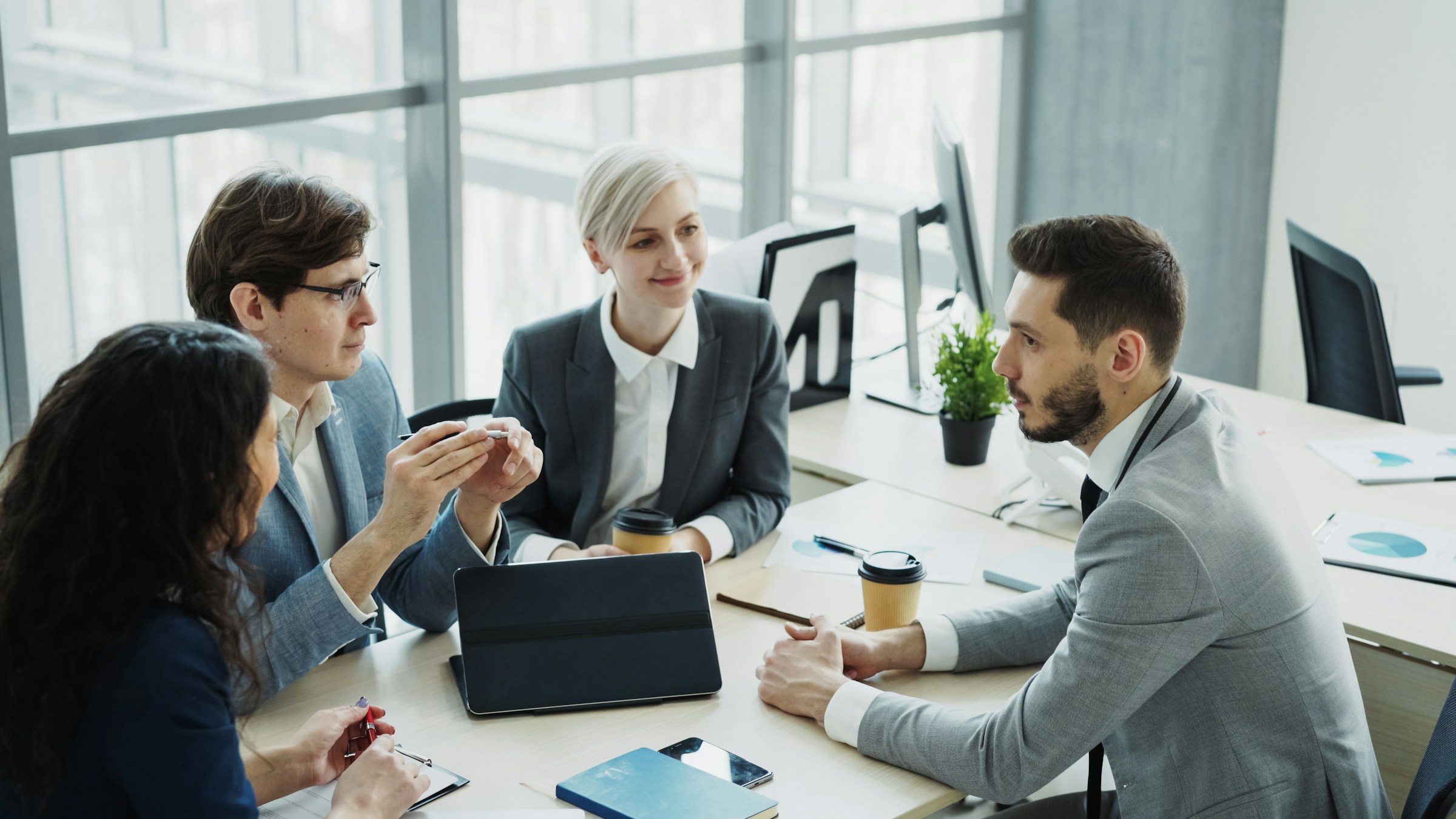 Four consultants in discussion around a meeting table in a daylit office