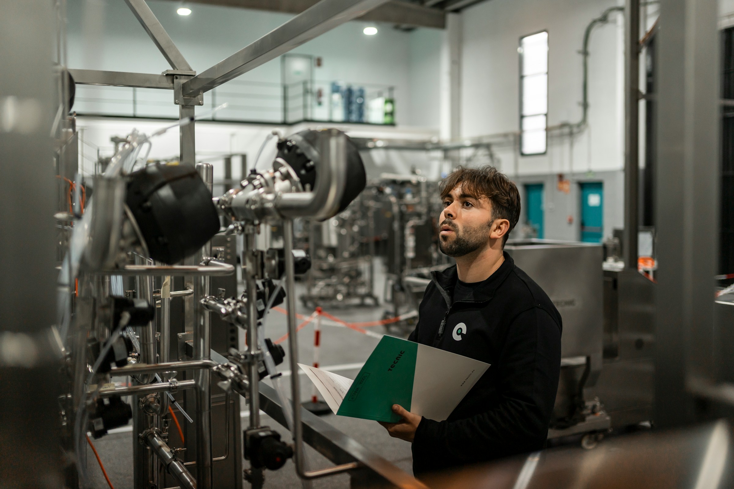Technician reviewing an industrial piping installation against technical documentation in a validation room
