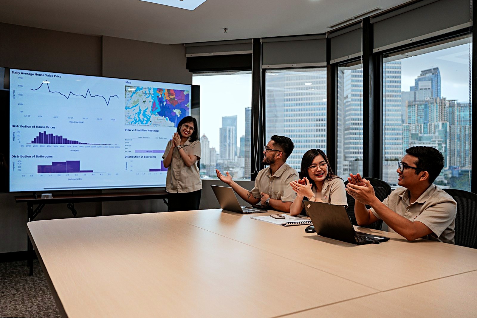 Team applauding a colleague presenting performance dashboards in a meeting room