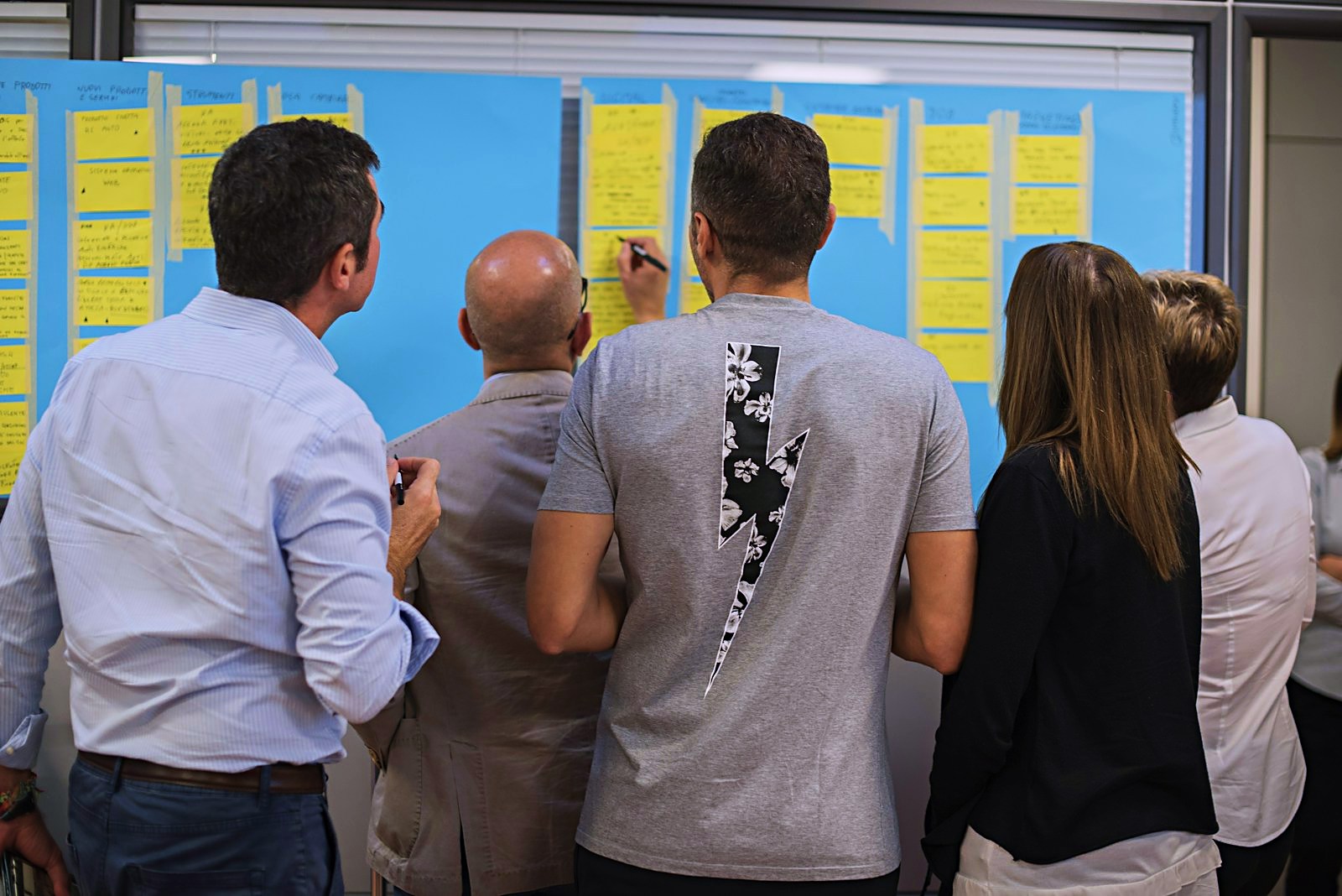 Team working through ideas on a wall of notes during a facilitated workshop